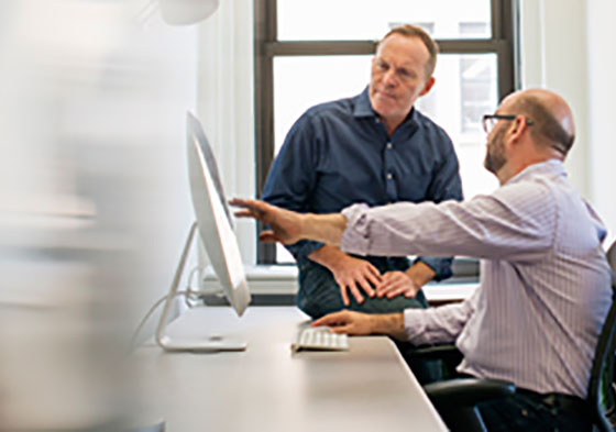 Two men sitting in front of a monitor